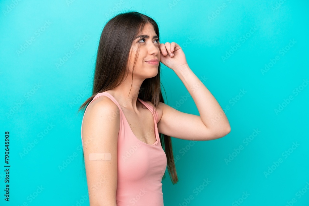 Young caucasian woman with band aids isolated on blue background having doubts and with confuse face expression