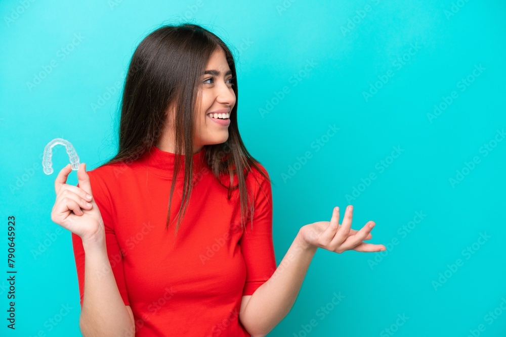 Young caucasian woman holding a envisaging isolated on blue background with surprise facial expression Young caucasian woman holding a envisaging isolated on blue background with surprise facial expression