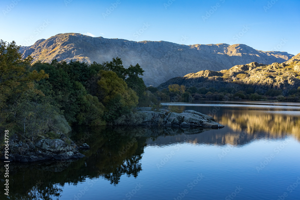 Sanabria Lake Natural Park in autumn at sunset with the mountains reflected in the water, Zamora, Castilla y León, Spain.