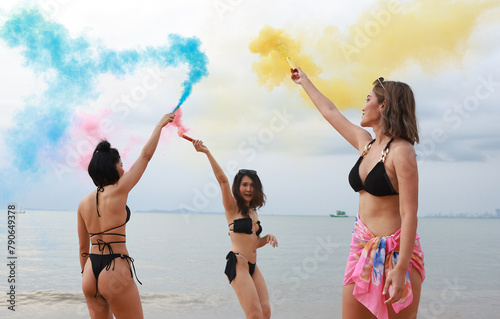 Joyful of Asian lady friend wearing bikini playing color smoke on the beach, Summer holiday and relaxing concept , summer holiday on tropical beach
