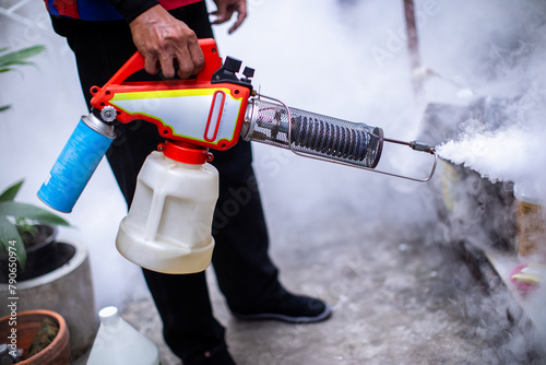 Officials are spraying mosquito repellent in the area of house to prevent dengue mosquitoes as carriers of dengue fever. The officer useing fogging machine spray mosquito repellent for stop dengue