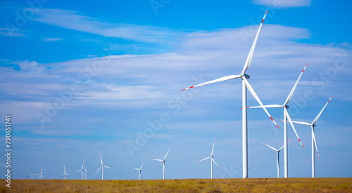 Fleet of power generators in motion. The blades of the wind farm rotate against the sky. The concept of extracting electricity from renewable sources. Wind turbine to generate electricity.