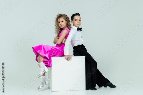 curly-haired girl and a boy engaged in ballroom dancing sit posing at a photo shoot