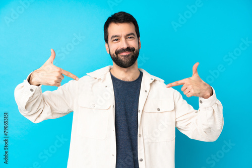 Young handsome man with white corduroy jacket over isolated blue background proud and self-satisfied