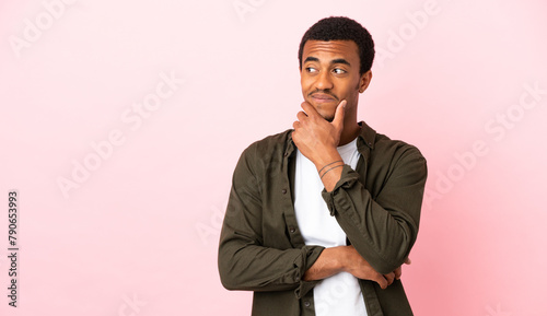 African American man on copyspace pink background thinking an idea while looking up