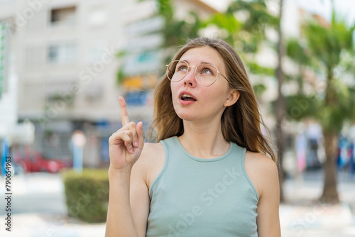 Young blonde woman with glasses at outdoors intending to realizes the solution while lifting a finger up