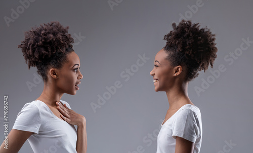 Black woman whispers; her reflection smiles knowingly photo