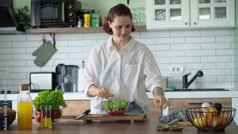 A young Caucasian woman prepares a salad of fresh organic vegetables in a bright kitchen. A young Caucasian woman prepares a salad of fresh organic vegetables in a bright kitchen.