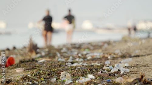 Environmental issue, plastic pollution on bali beach with blurred tourists in background photo