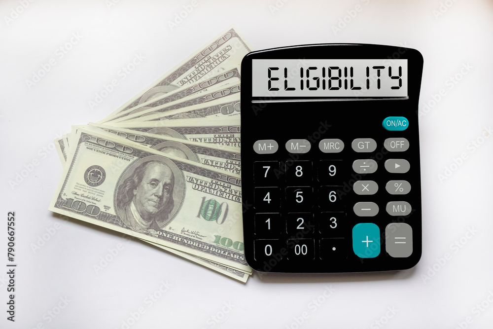 Business concept. The text Eligibility is written on a calculator on a white background next to dollars Business concept. The text Eligibility is written on a calculator on a white background next to dollars