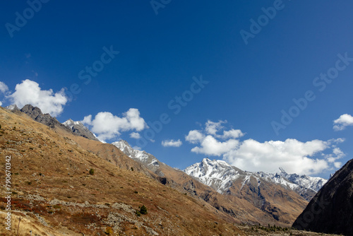 Landscape of the mountains. View of snow covered mountains with blue sky, white cloud with trees on the slopes of mountains at Kashmir.
