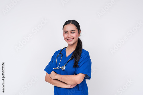 Confident young Asian female caregiver in blue scrubs with a stethoscope, isolated on white
