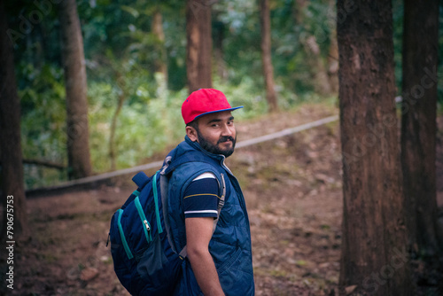 Young man with backpack hiking in forest. Travel and adventure concept.