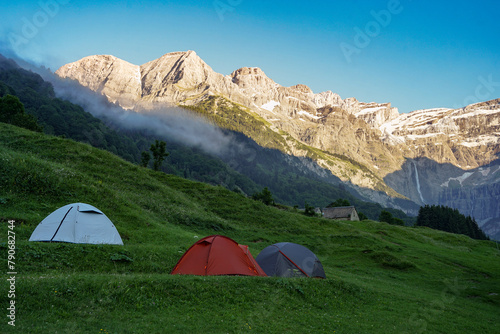 Three tents on meadow in high mountains during sunset in french Pyrenees near Gavarnie Falls waterfall  France  popular hiking destination