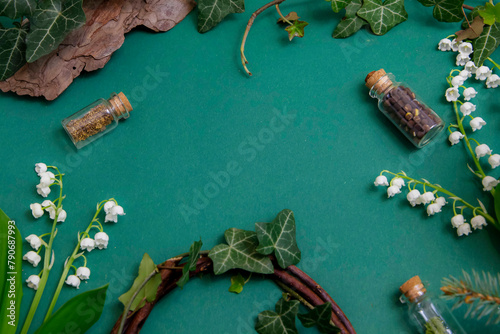Kompozycja na stole na zielonym tle w otoczeniu roślinności: bluszcz, konwalie.  © Katarzyna
