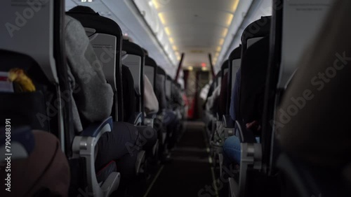 View of aisle pathway on airplane with passengers on seats. Unrecognisable passengers sitting in chairs on the plane. Video can be used for your video.