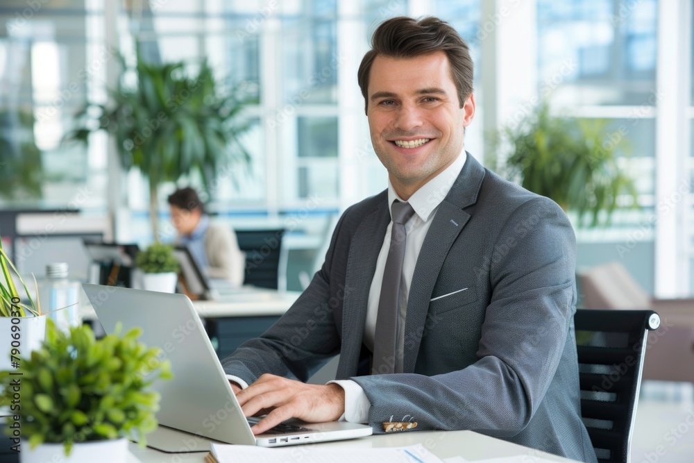Businessman Office: Smiling Businessman Using Laptop at Desk in Office Environment Businessman Office: Smiling Businessman Using Laptop at Desk in Office Environment