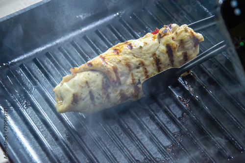Juicy chicken breast with grill marks cooking on a black grill pan