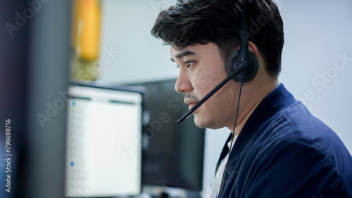 close up asian man call center agent wear headset device and  working in operation room with soling problem to client at desktop table for network engineering  and help desk concept	 photo