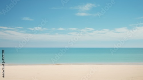 A tranquil and picturesque view of a sandy beach with clear blue ocean and sky