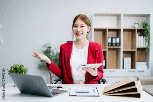 Confident Asian woman with a smile standing holding notepad and tablet at the ffice.. photo