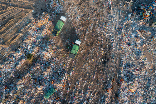 Aerial top down view of garbage trucks unload pile of waste at landfill. Dump of unsorted waste garbage pile in trash dump. Environmental pollution and ecological disaster. View from drone