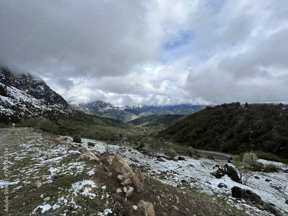 Tseylomsky pass in Ingushetia. A trip uphill to the Tsei Loam pass on a cloudy spring day. Panorama of the high cliffs of the Dzheyrakh gorge. North Caucasus, Russia