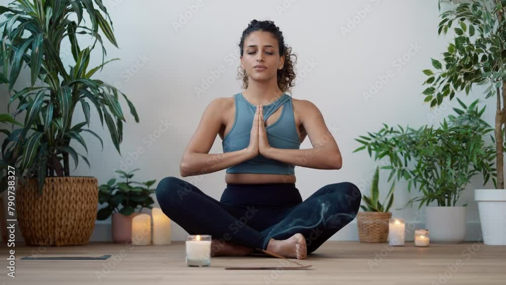 Video of sporty young woman doing yoga and hypopressive exercises while staying in lotus position in living room at home.