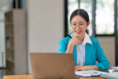 Focused businesswoman working on a laptop at a wooden desk. Professional dedication and business task concept.