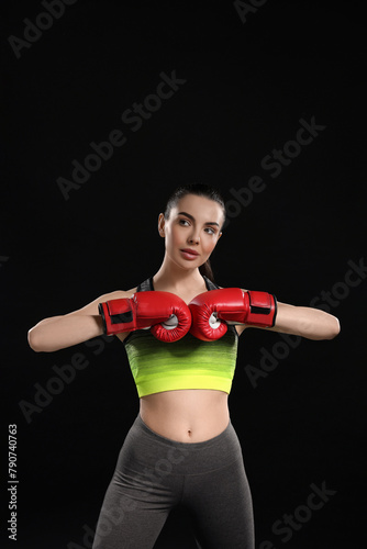 Portrait of beautiful woman in boxing gloves on black background © New Africa