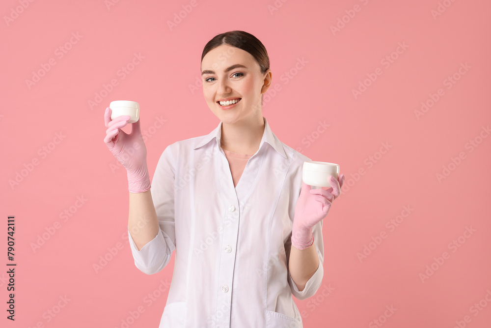 Cosmetologist with cosmetic products on pink background Cosmetologist with cosmetic products on pink background