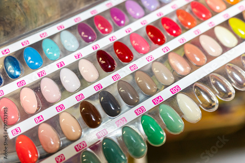 A display of painted nail samples in a store, featuring various colors and designs. The samples are neatly arranged, showcasing a diverse range of nail polishes, from bright hues to subtle shades.