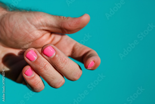 Man s hand with pink nail color on blue studio background