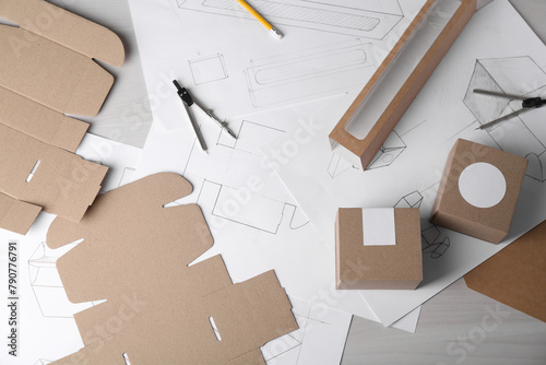 Creating packaging design. Drawings, boxes and stationery on light wooden table, flat lay photo