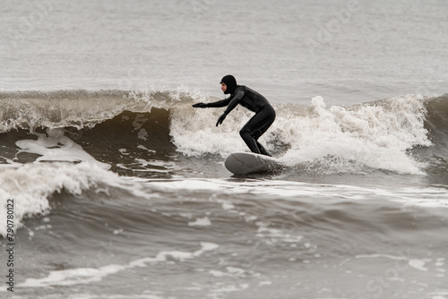 Male surfer riding a surfboard on a high wave, keeping his balance