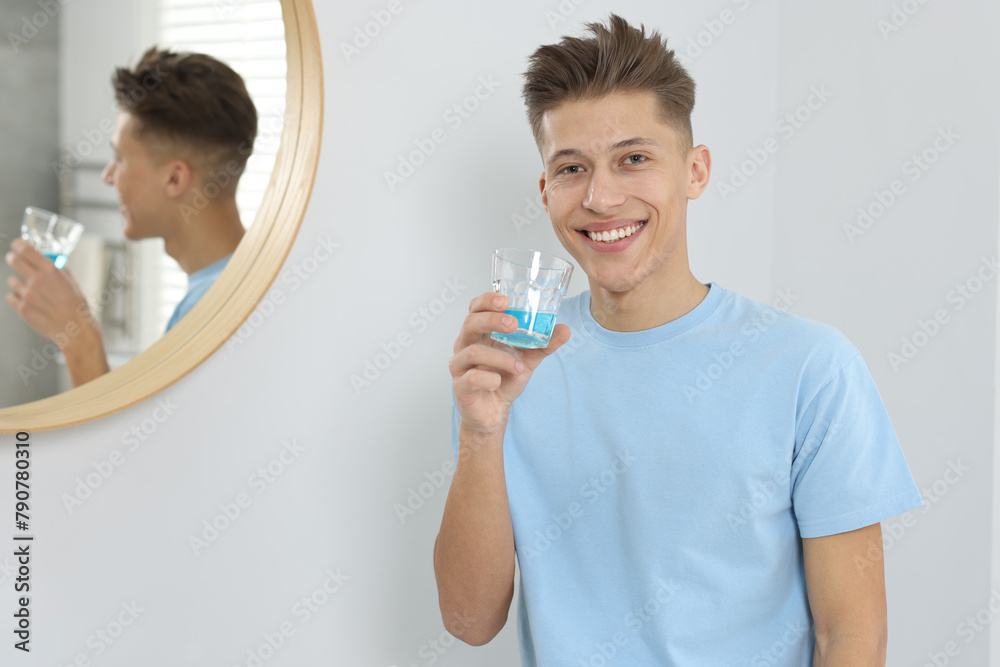 Young man with mouthwash in bathroom. Oral hygiene Young man with mouthwash in bathroom. Oral hygiene