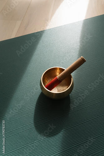 Singing meditation bowl on a yoga mat, ray of sunlight shines on a yoga mat, copy space.