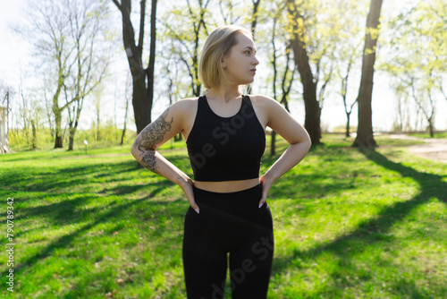beautiful young athletic girl in leggings with a model figure on a morning jog in a green sunny park on the street. Fitness, warm-up and outdoor sports. beauty and health