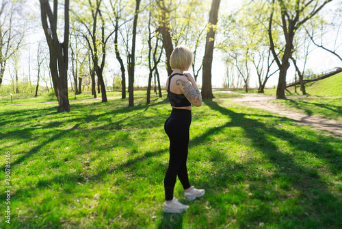 beautiful young athletic girl in leggings with a model figure on a morning jog in a green sunny park on the street. Fitness, warm-up and outdoor sports. beauty and health