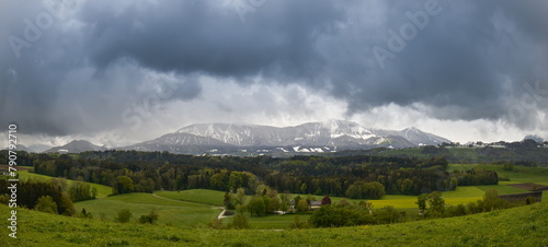 Ein typischer Tag im April am Rande der Alpen - Schnee in den Bergen und grüne Landschaften im Tal