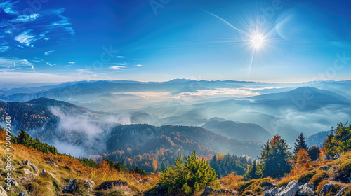 Panoramic view from autumn mountain peak at sunrise in blue sky with misty valley below © boxstock production
