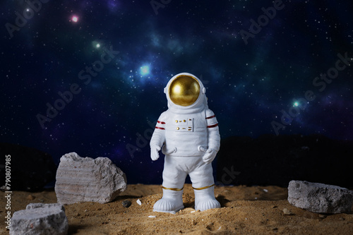 Figurine of astronaut over blue star sky background, copy space. Toy of spaceman. Space and space flights concept. Day of cosmonauts.