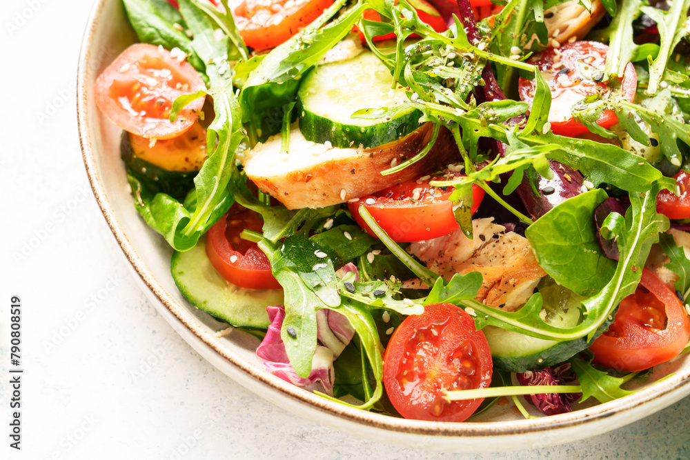 Green salad with baked chicken breast, fresh salad leaves and vegetables. Close up.