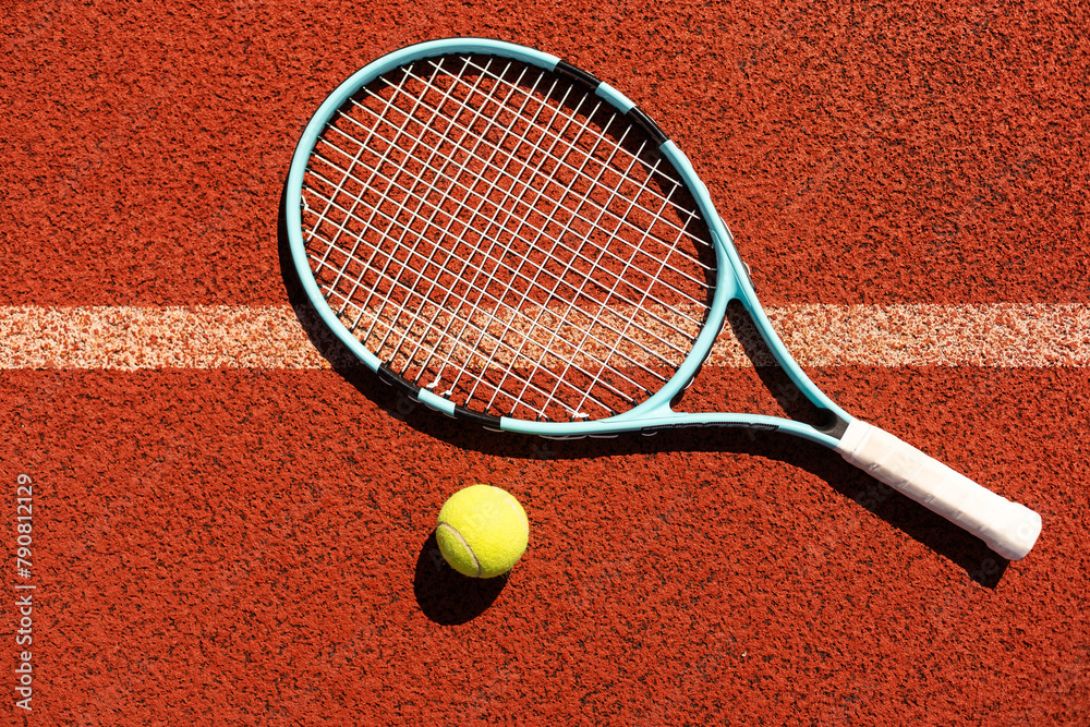 Racket with a tennis ball on a red clay court.