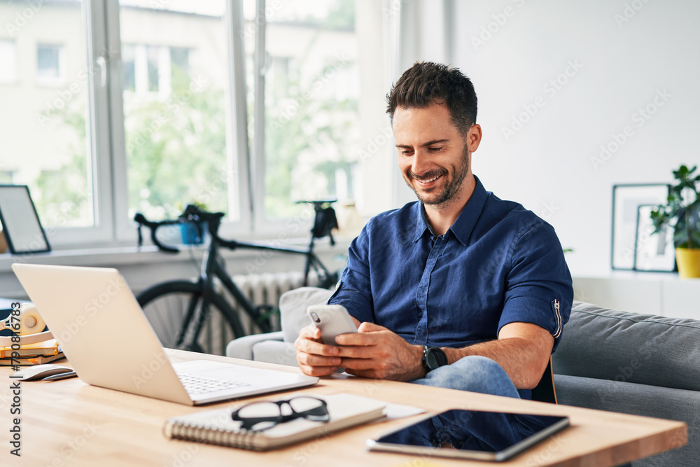 Carefree man using phone while working from home office Carefree man using phone while working from home office