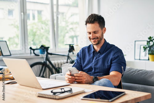 Carefree man using phone while working from home office