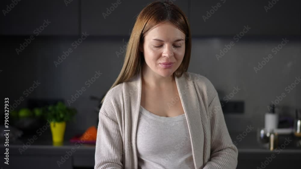 A pregnant woman prepares tea with milk while standing in a modern kitchen in an apartment. The woman enjoys the aroma of tea and after taking a sip, closes her eyes, smiling A pregnant woman prepares tea with milk while standing in a modern kitchen in an apartment. The woman enjoys the aroma of tea and after taking a sip, closes her eyes, smiling