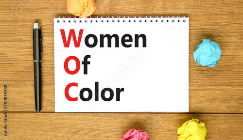 WOC women of color symbol. Concept words WOC women of color on beautiful white note. Beautiful wooden table wooden background. Business WOC women of color social issues concept. Copy space.
