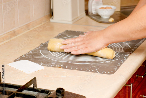 female hands form baking dough on a cooking mat