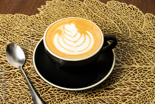 cappuccino with art and spoon served in coffee cup isolated on wooden table side view of cafe hot drink